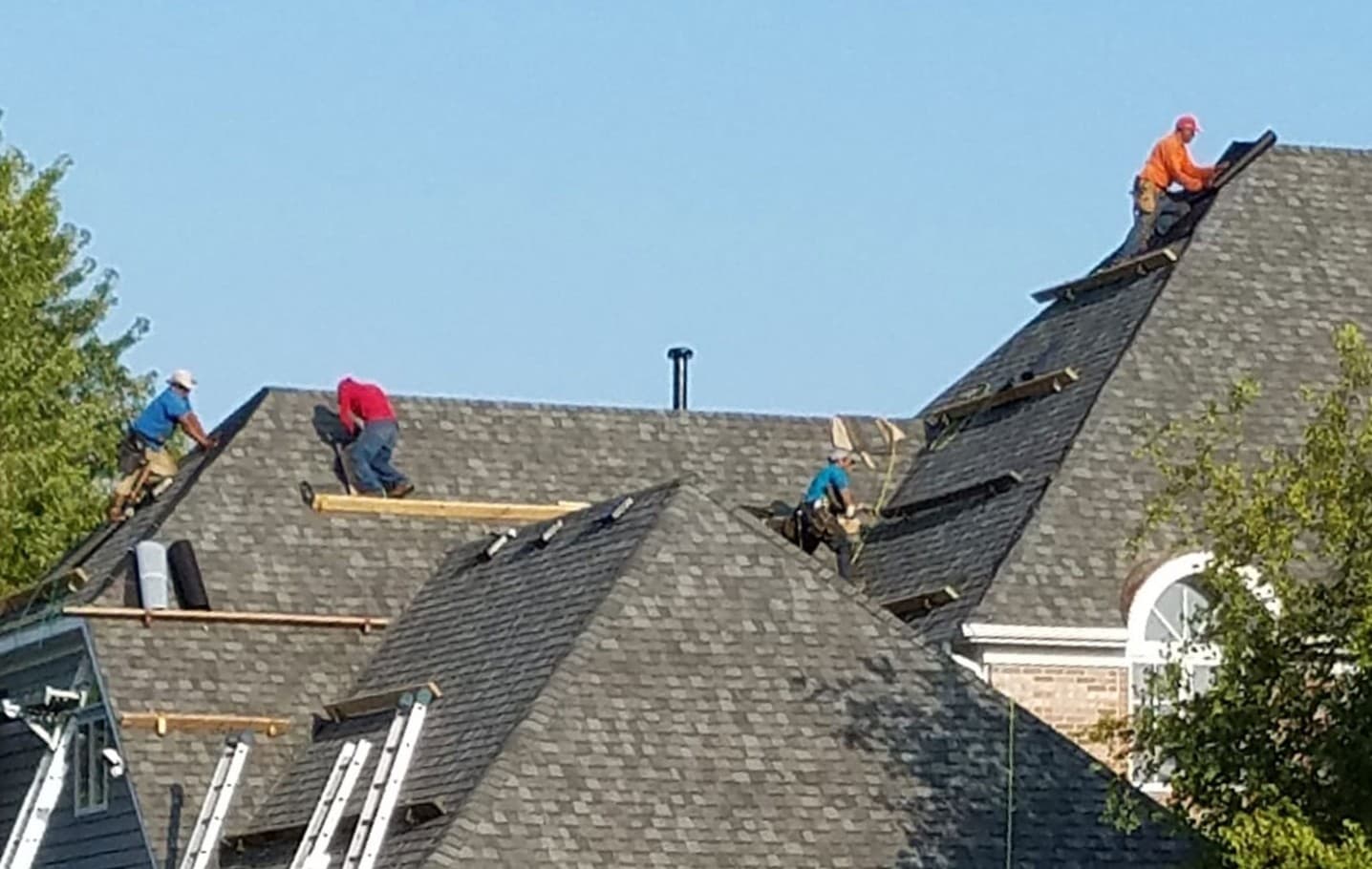 Roofing crew installing shingles on residential roof